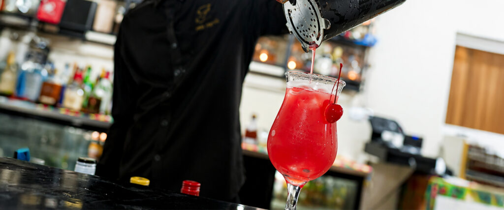 Bartender pouring a vibrant red tropical cocktail at Felicity Rooftop Restaurant, showcasing signature Caribbean drinks in St Lucia.