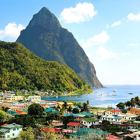Panoramic view of Soufrière St Lucia with the Pitons, colorful town, and Caribbean Sea, highlighting a restaurant with an oceanview in St Lucia at Felicity Rooftop Restaurant.
